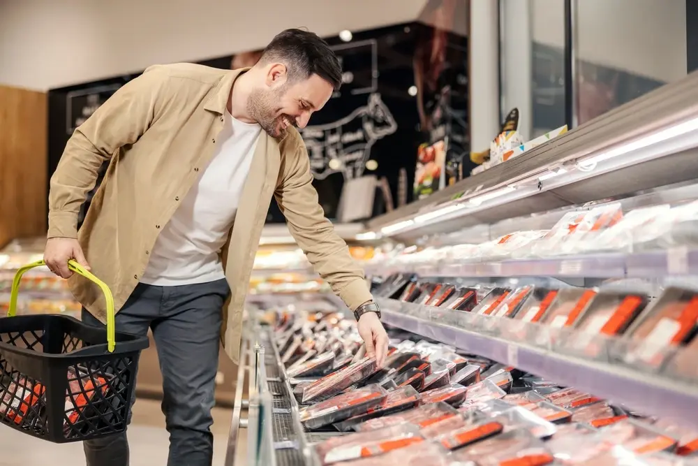 man looking at packaged meat in a cooler